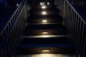 IMG_7023 | LandCo Group Nighttime outdoor staircase lit by embedded step lights, with metal railings on both sides leading up to a building entrance.