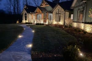 IMG_7033 | LandCo Group Night exterior of a modern stone-and-siding house, with a curved, lit stone path leading to the front entrance.