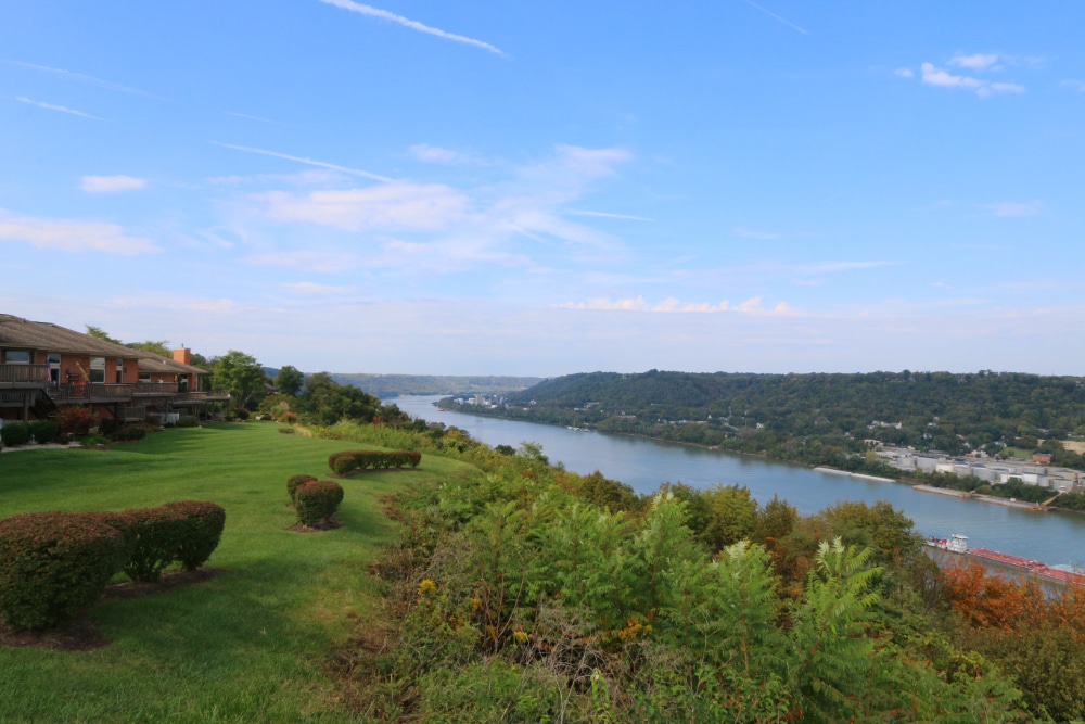 Villa Hills | LandCo Group Well-manicured lawn and trimmed shrubs overlook a winding river with tree-covered hills in the distance on a sunny day.