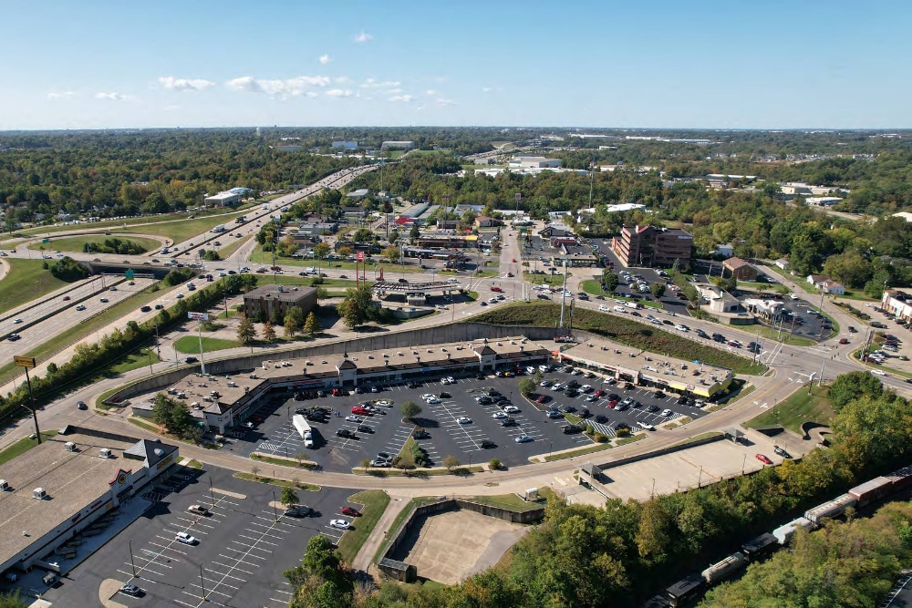 Crescent-Springs-Kentucky | LandCo Group Aerial view of a suburban shopping center with a large circular parking lot and surrounding roads.