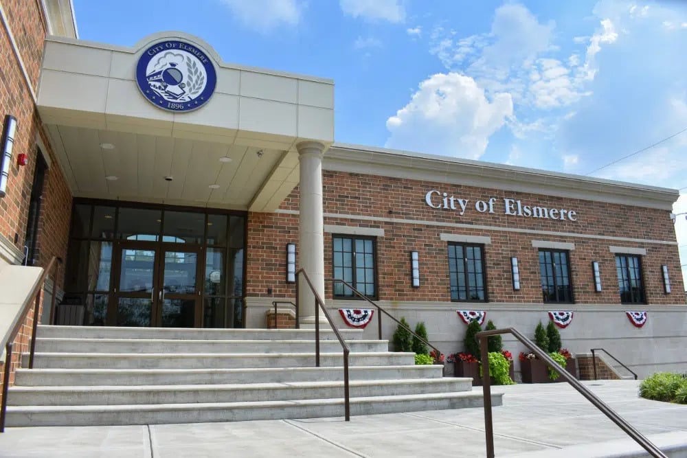 Elsmere | LandCo Group Front exterior of City of Elsmere municipal building with brick facade, glass doors, and a wide staircase.