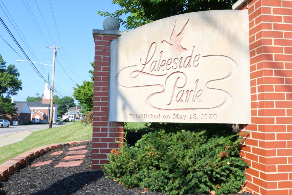 Lakeside Park | LandCo Group Stone sign reading Lakeside Park with a curved script and a bird motif, flanked by red brick pillars and greenery; note: Established May 12, 1930 on the sign.