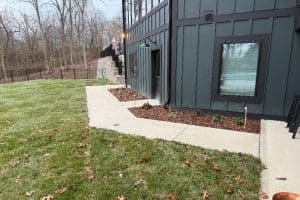 Union Full Landscape 11 | LandCo Group Exterior view of a dark-green building with windows and a door, a concrete sidewalk, and mulched plant beds along the foundation.