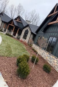 Union Full Landscape 4 | LandCo Group Exterior view of a modern townhouse complex with stone and dark siding, peaked roofs, and landscaped mulched beds in the foreground.
